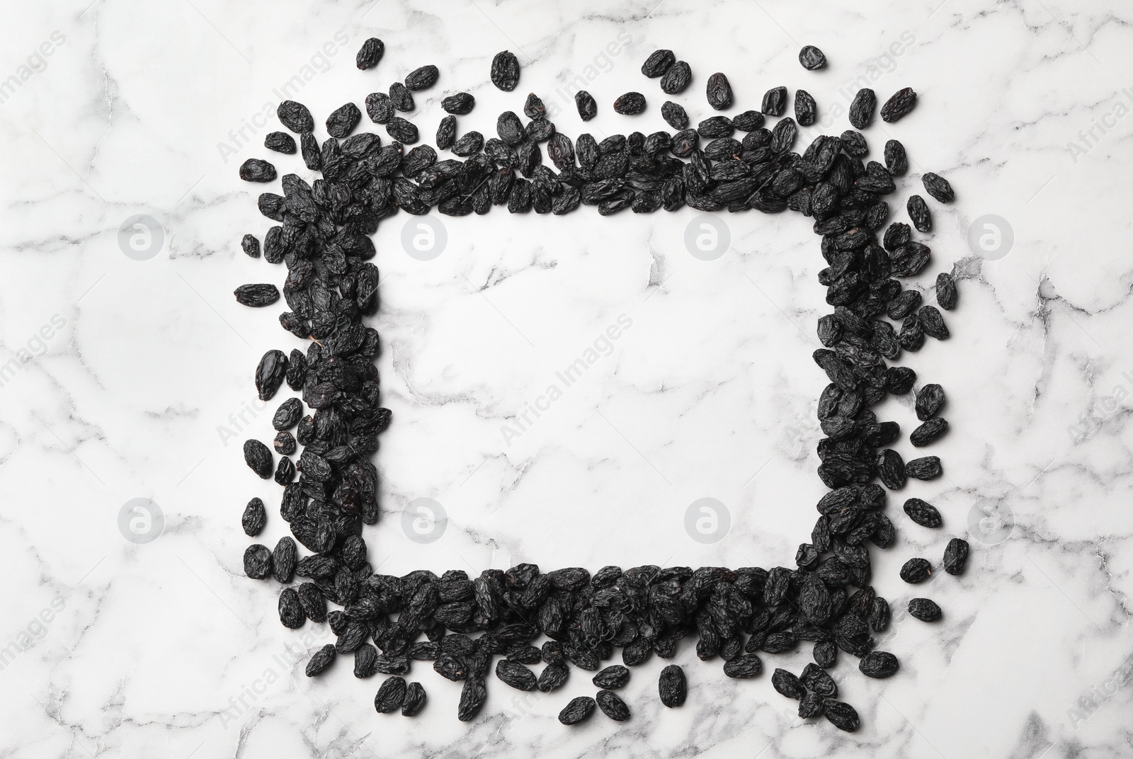 Photo of Frame of raisins and space for text on marble background. Dried fruit as healthy snack