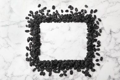 Frame of raisins and space for text on marble background. Dried fruit as healthy snack