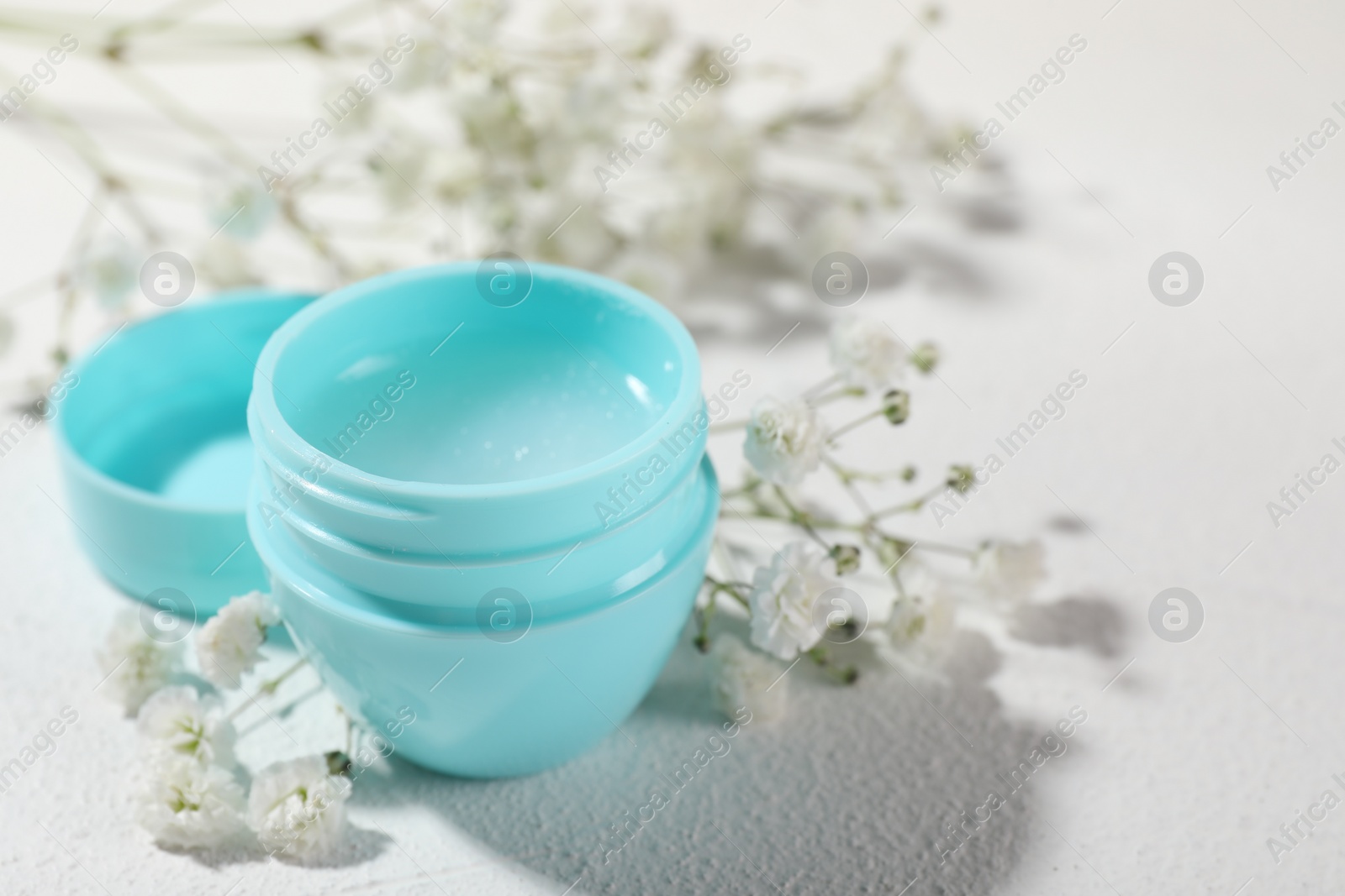 Photo of Lip balm and gypsophila on white background, closeup. Space for text