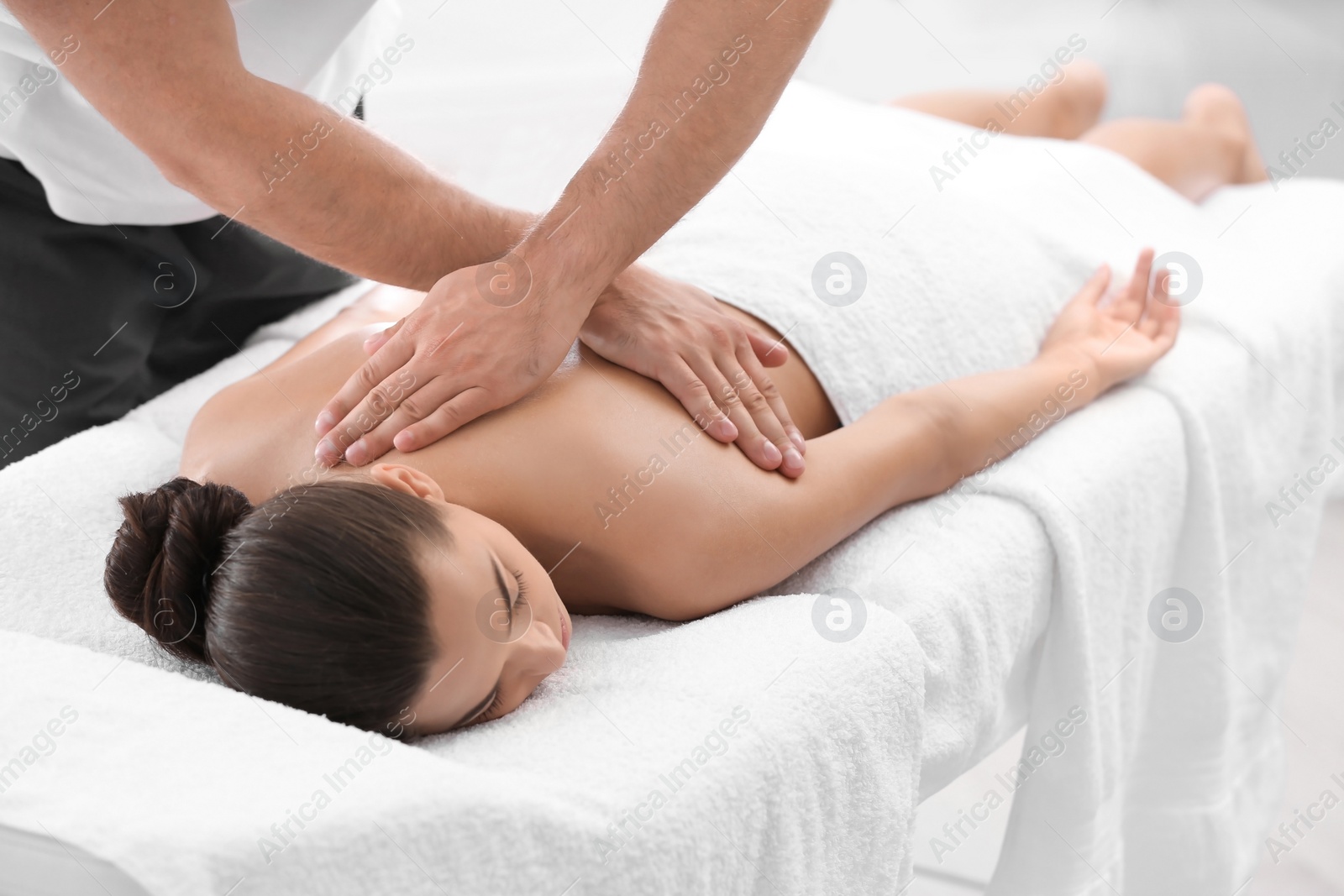 Photo of Relaxed woman receiving back massage in wellness center