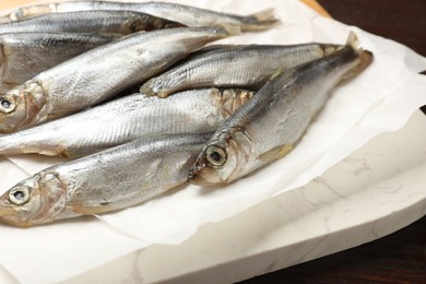 Photo of Fresh raw sprats on wooden table, closeup