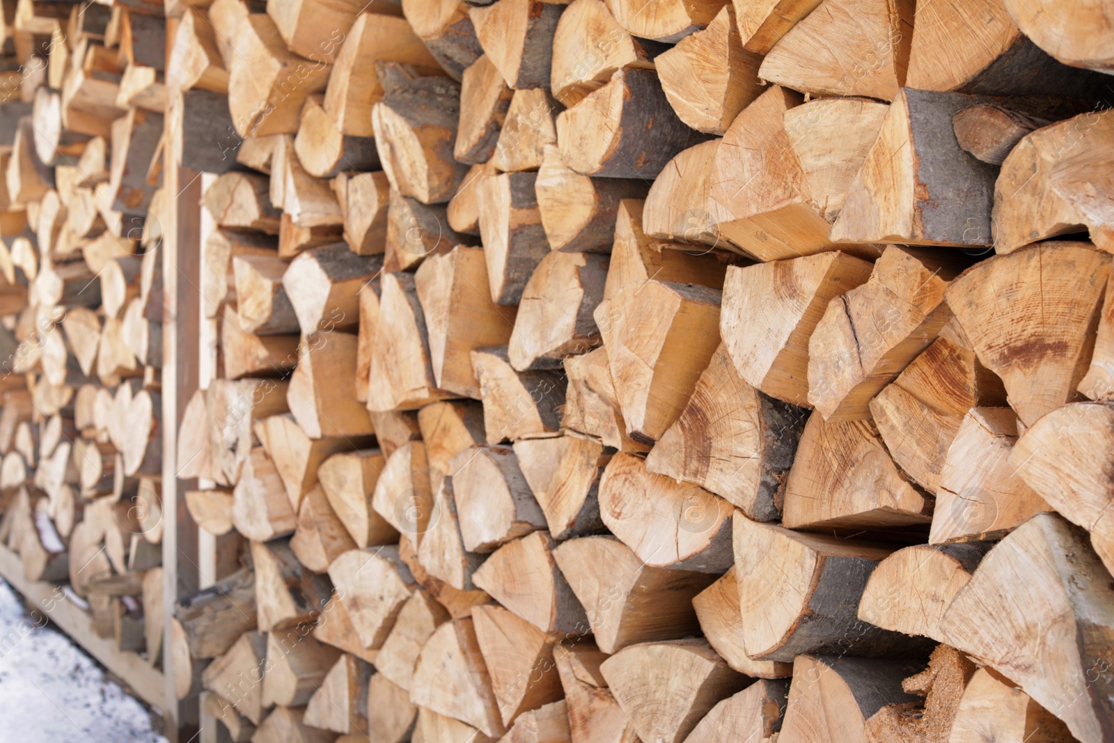 Photo of Stacked firewood outdoors, closeup. Heating house in winter