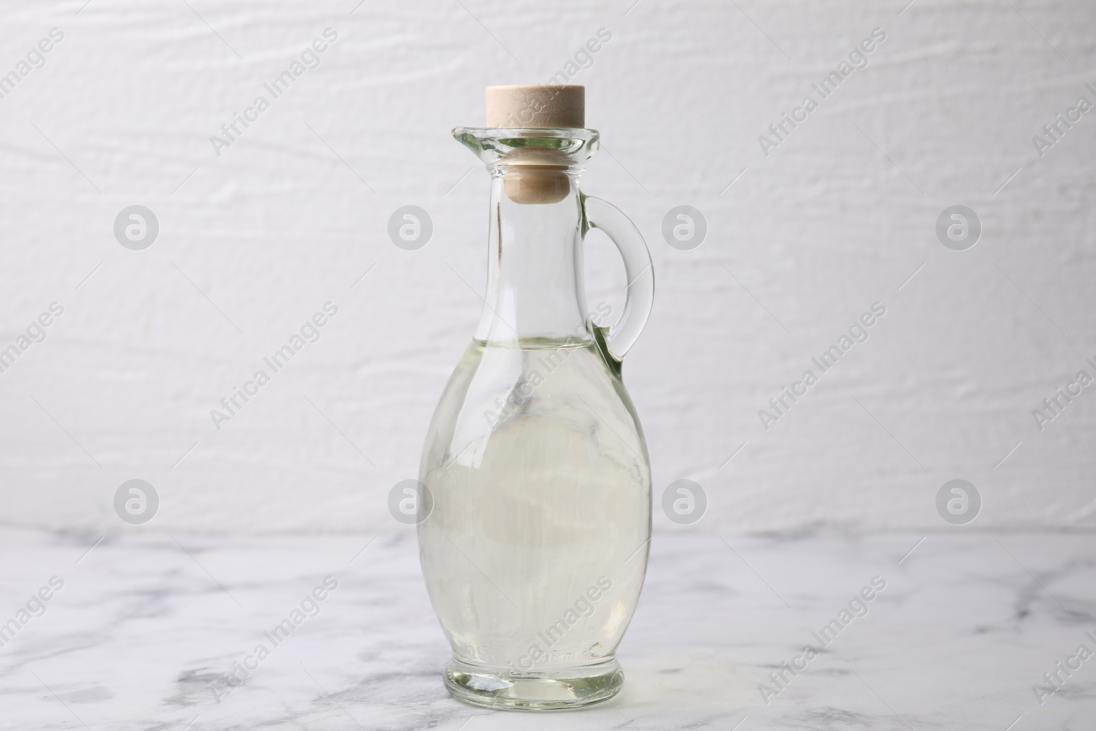 Photo of Vinegar in glass jug on white marble table