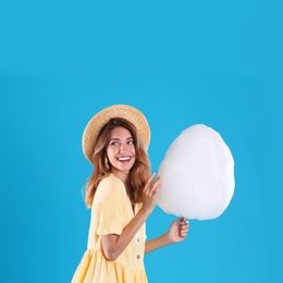 Photo of Happy young woman with cotton candy on blue background