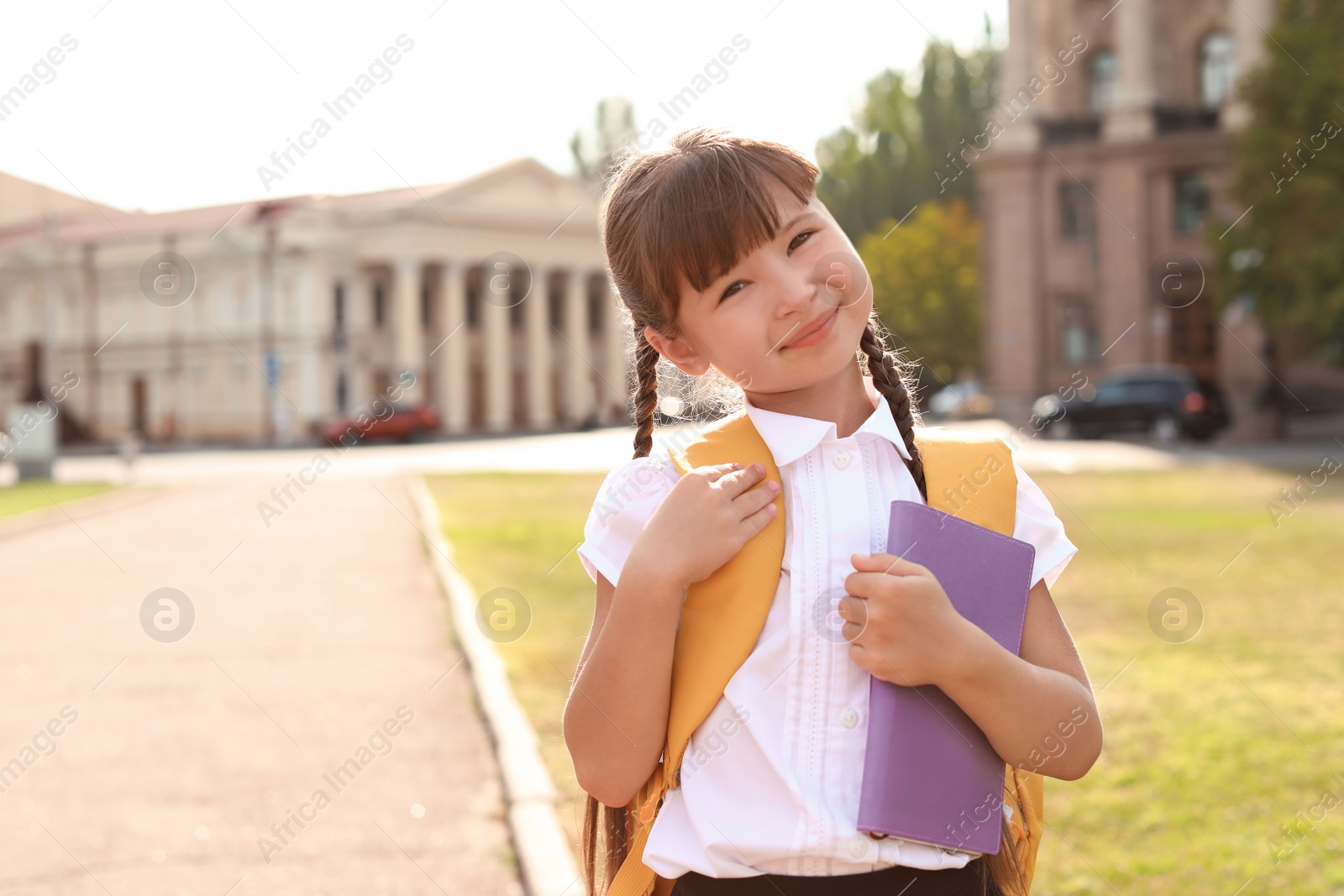 Photo of Little girl with backpack and notebook outdoors. Stationery for school