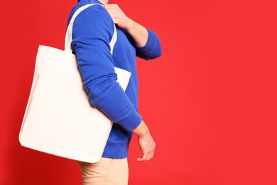 Young man with eco bag on red background, closeup. Space for text