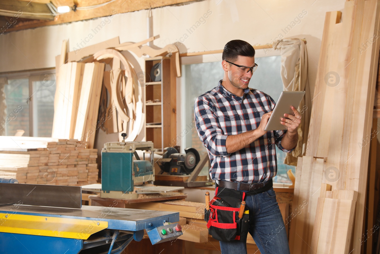 Photo of Professional carpenter with tablet in modern workshop