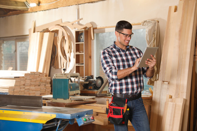 Professional carpenter with tablet in modern workshop