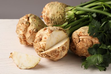 Photo of Fresh raw celery roots on white wooden table, closeup