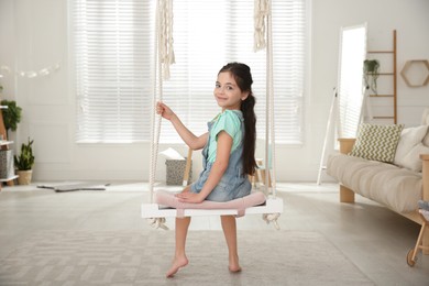 Photo of Cute little girl playing on swing at home