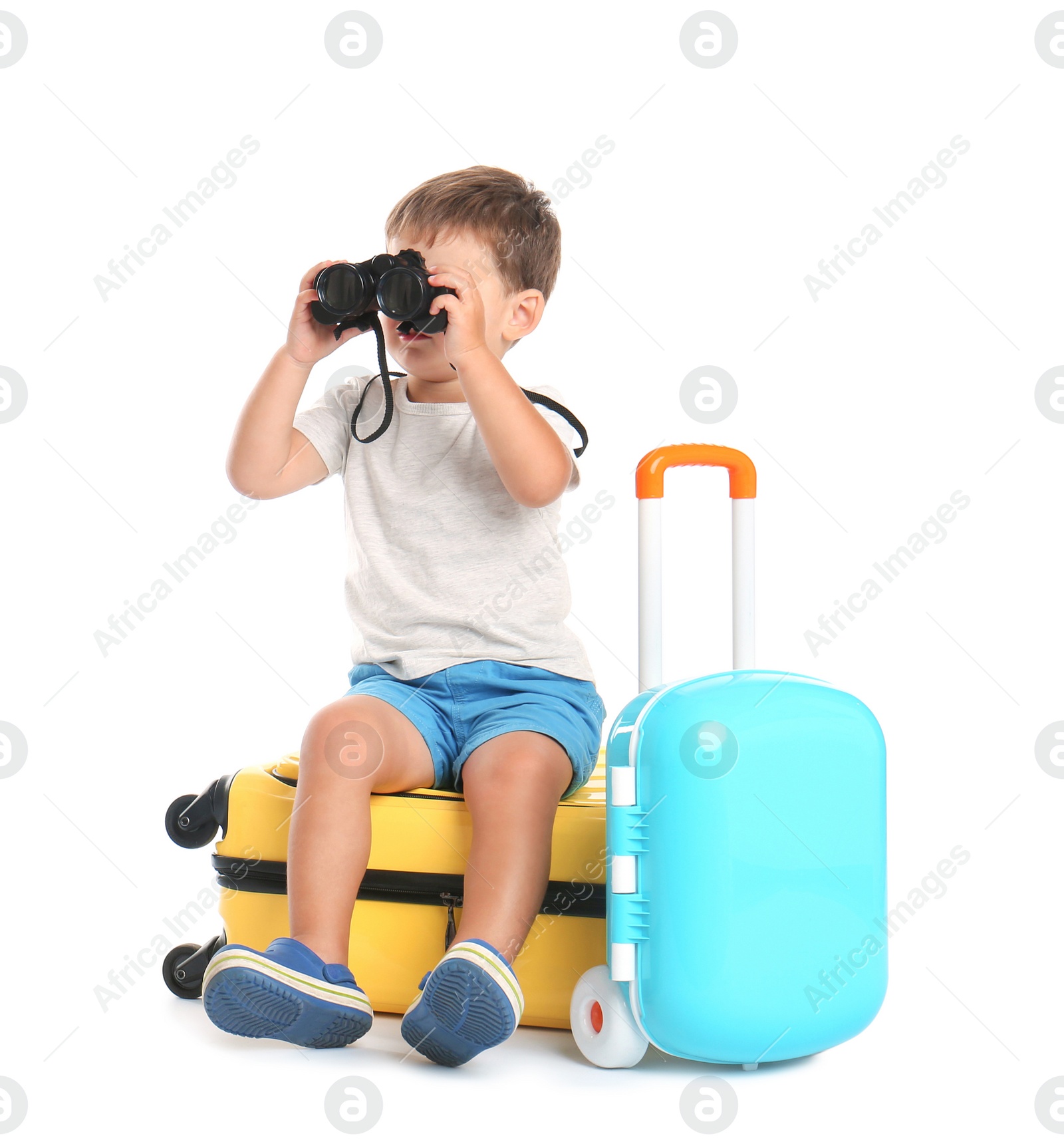 Photo of Cute little boy with binocular and suitcases on white background