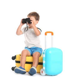 Cute little boy with binocular and suitcases on white background