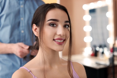 Photo of Professional hairdresser working with client in beauty salon