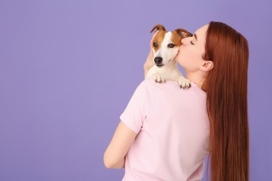 Photo of Woman kissing cute Jack Russell Terrier dog on violet background, back view. Space for text