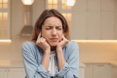 Emotional young woman covering her ears with fingers at home