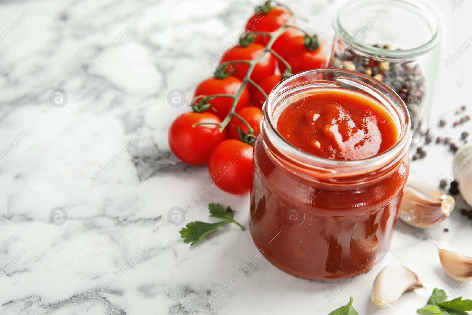 Photo of Composition with jar of tasty tomato sauce on marble table. Space for text