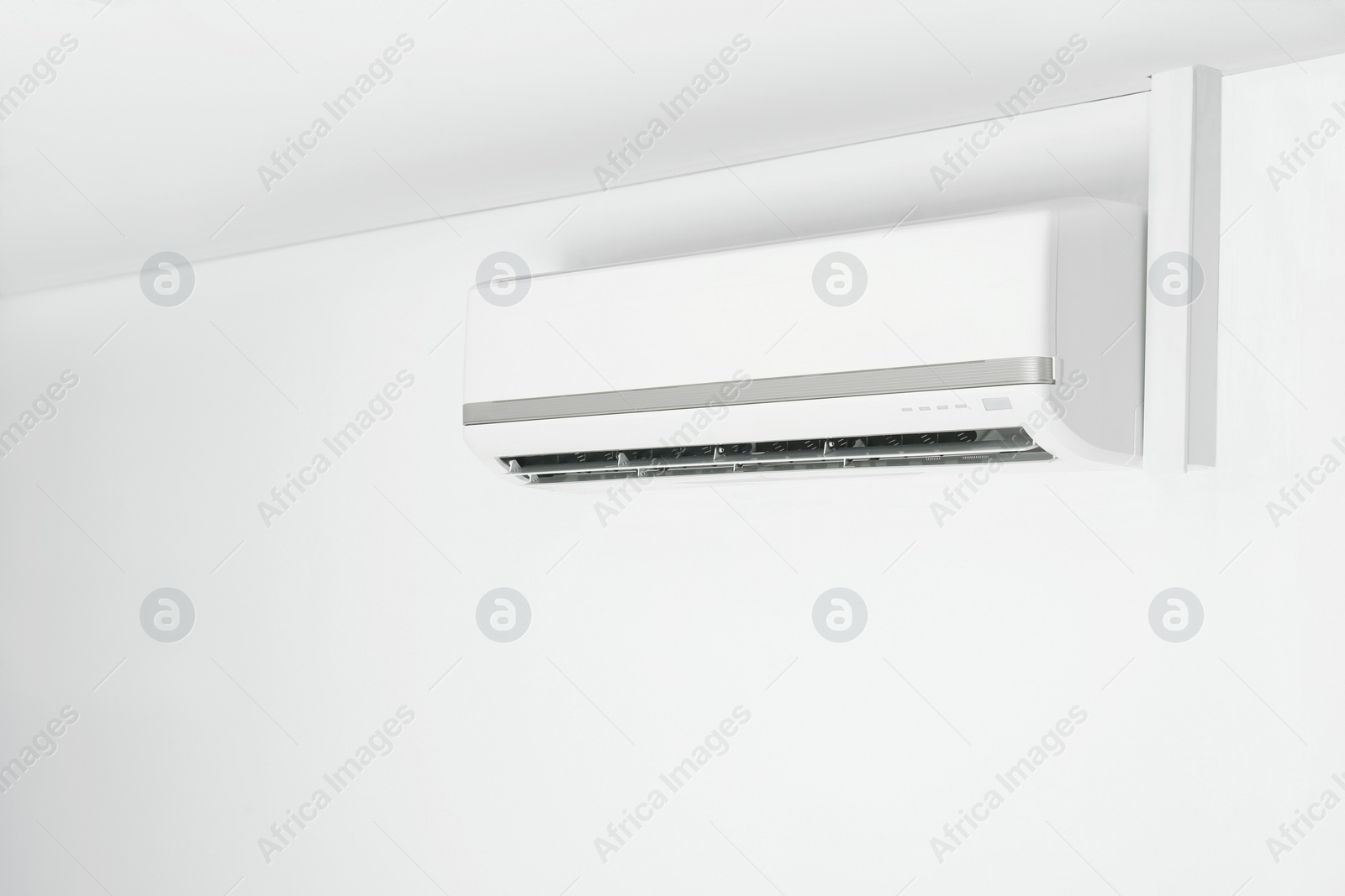 Photo of Modern air conditioner on white wall indoors. Space for text