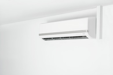 Modern air conditioner on white wall indoors. Space for text