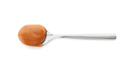 Spoon with delicious caramel on white background