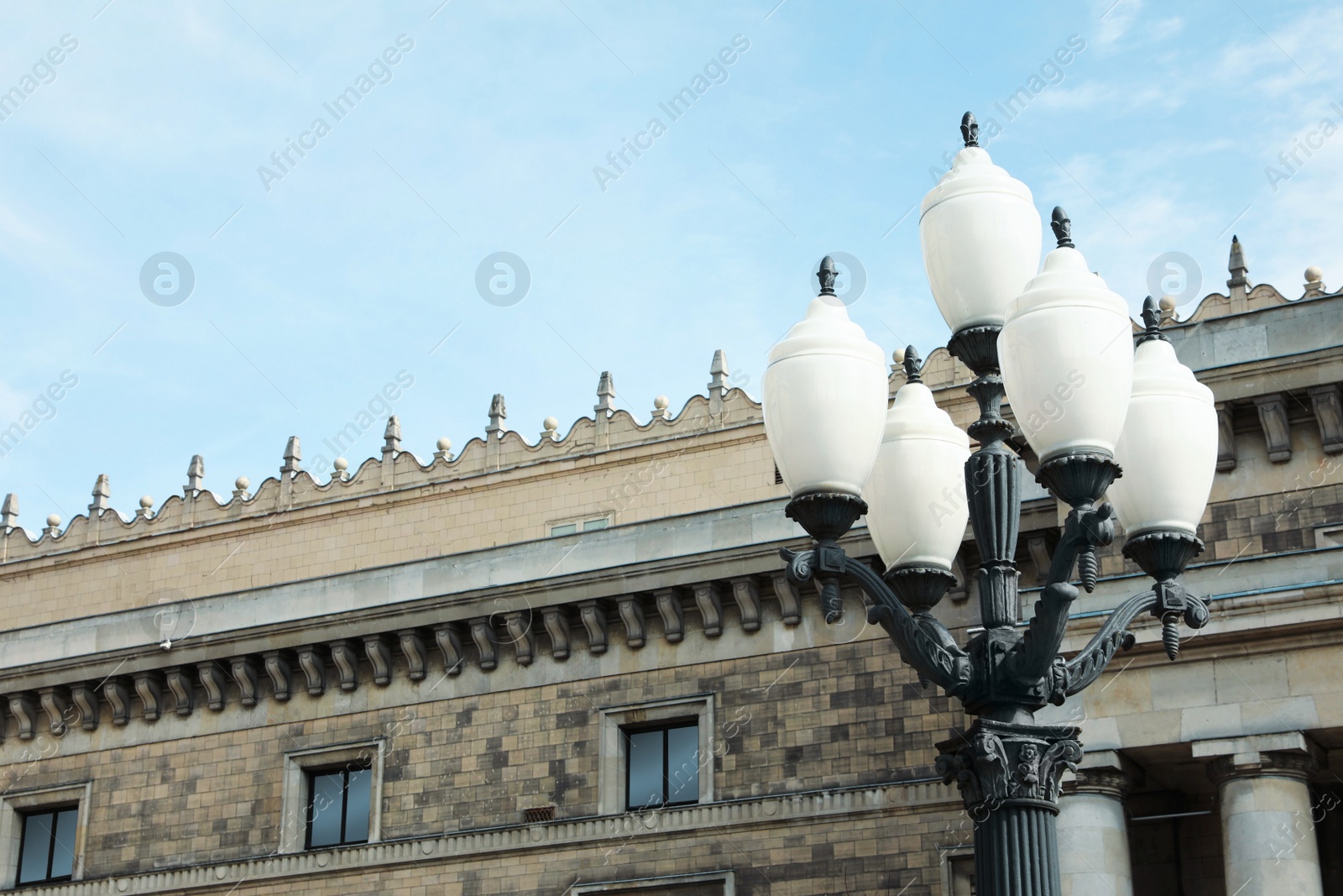 Photo of Old fashioned street light lamp near building against cloudy sky