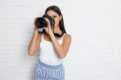 Photo of Professional photographer working near white brick wall in studio. Space for text