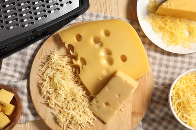 Photo of Grated, cut cheese and grater on wooden table, flat lay