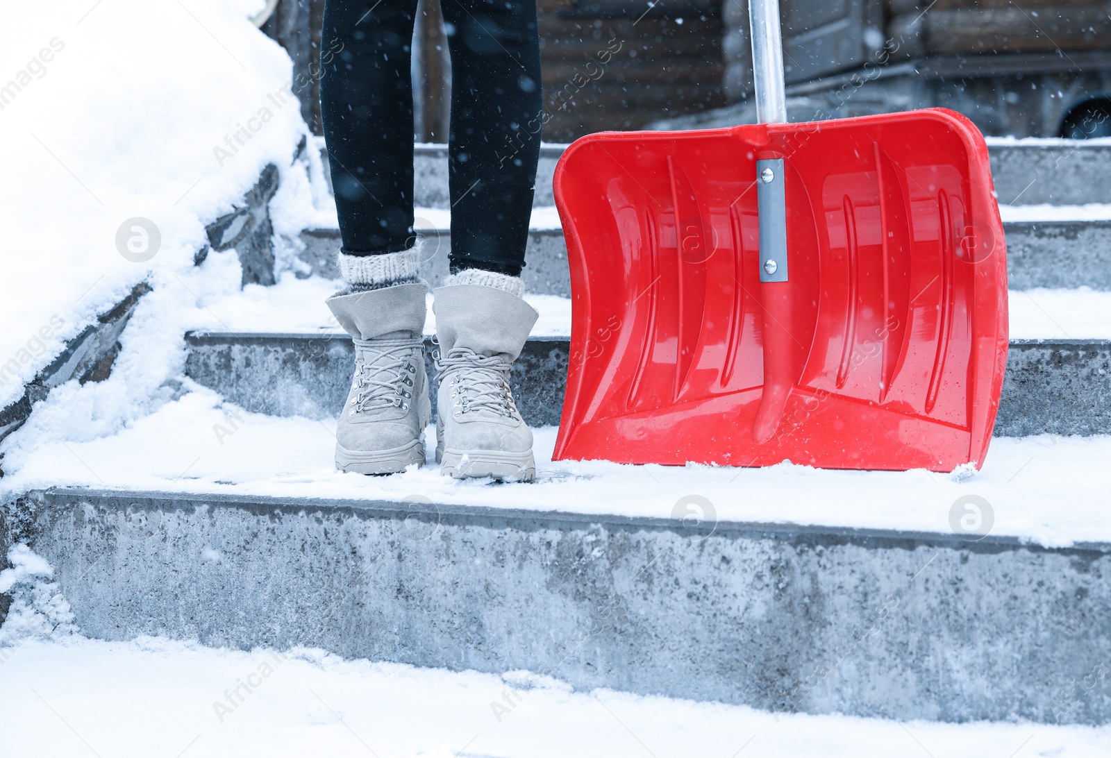 Photo of Woman with red snow shovel outdoors. Winter weather