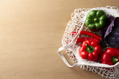 Photo of Different fresh vegetables in eco mesh bag on wooden table, top view