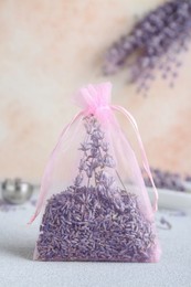 Photo of Scented sachet with dried lavender flowers on light gray table