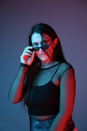 Photo of Portrait of beautiful young woman with sunglasses on color background