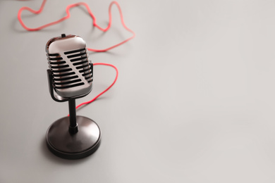 Photo of Vintage microphone on light grey table, space for text