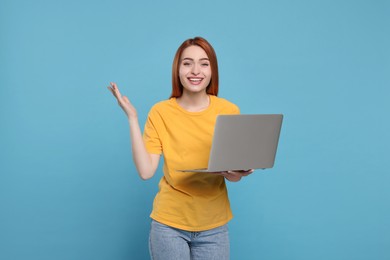 Photo of Happy young woman with laptop on light blue background