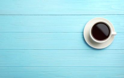 Photo of Ceramic cup with hot aromatic coffee on wooden background, top view