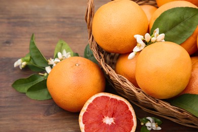 Photo of Wicker basket with fresh grapefruits and green leaves on wooden table