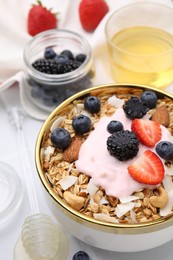 Photo of Tasty granola, yogurt and fresh berries in bowl on white table, closeup. Healthy breakfast