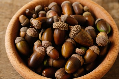 Photo of Bowl of acorns on wooden table, closeup