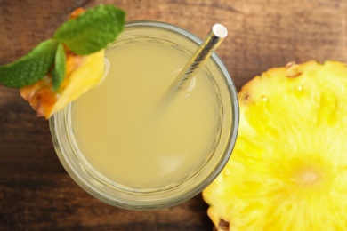 Photo of Delicious pineapple juice with fresh fruit and mint on wooden table, flat lay