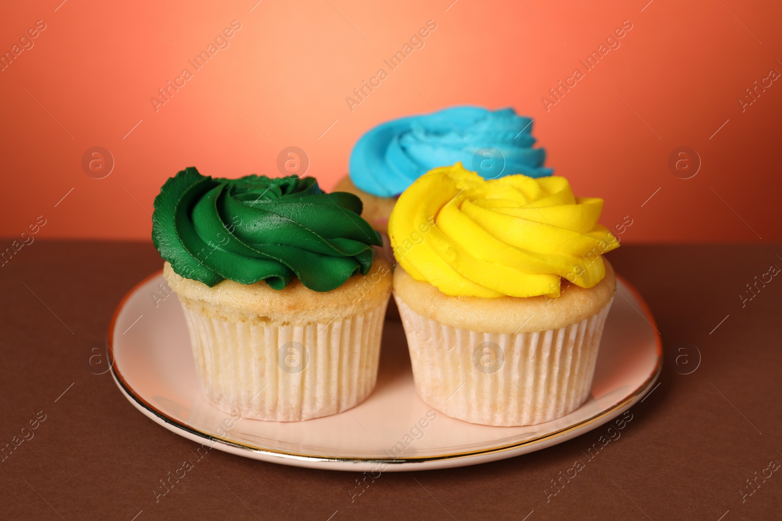 Photo of Delicious cupcakes with bright cream on color background