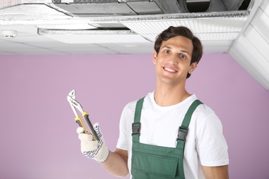 Photo of Male technician with pliers near air conditioner indoors