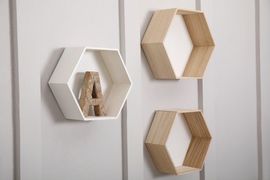 Photo of Honeycomb shaped shelves with decorative wooden letter on white wall