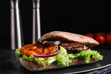 Photo of Delicious eggplant sandwich on slate board, closeup