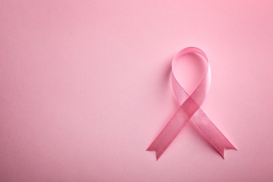 Photo of Pink ribbon on color background, top view with space for text. Breast cancer awareness concept