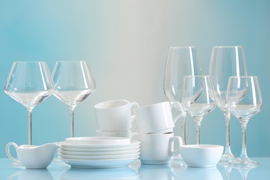 Photo of Set of many clean dishware and glasses on light blue table