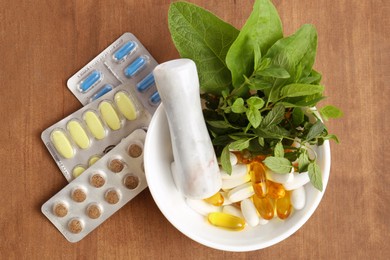 Photo of Mortar with fresh mint and pills on wooden table