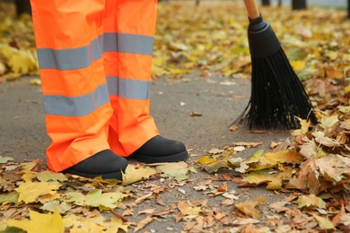 Photo of Street cleaner sweeping fallen leaves outdoors on autumn day