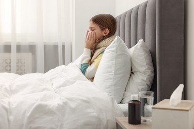 Photo of Sick girl with tissue coughing on bed at home