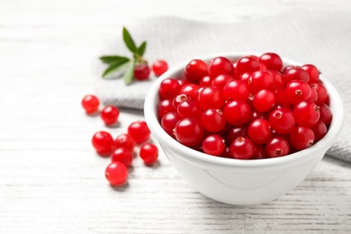 Photo of Tasty ripe cranberries on white wooden table, closeup. Space for text