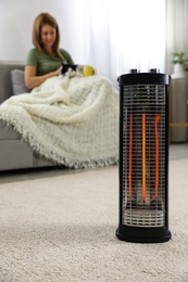 Photo of Woman with cat at home, focus on electric halogen heater