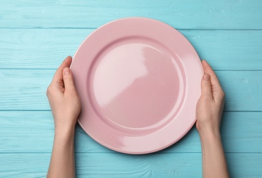 Photo of Woman with empty plate at wooden table, top view