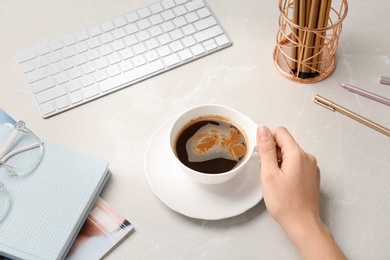 Young woman with cup of delicious coffee at table